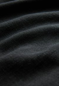 Sort stof med blød tekstur, der har subtile bølger og en let glans, viser fine, tætte vævninger og en ensartet farve gennem hele stoffet.