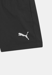 Zwarte shorts met een gladde textuur en een elastische tailleband. Voorzien van een opvallend wit Puma-logo aan de onderzijde. Eenvoudig ontwerp, zonder patronen.