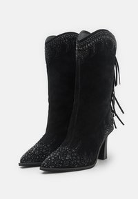 Botines de ante negro con punta afilada, decorados con acentos de cuentas y flecos, con una parte superior texturizada y tacón alto.