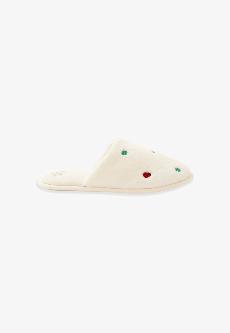 Chausson doux couleur crème à bout fermé, brodé de petites étoiles vertes et d'une coccinelle rouge, semelle plate et texture pelucheuse.