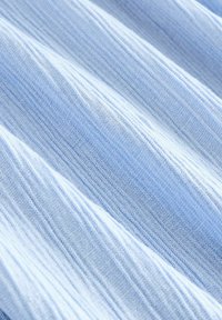 Svetlo modrá textúrovaná látka so subtílnymi pruhmi, ktorá má jemný, tkaný vzor. Materiál vyzerá ľahko a vzdušne.