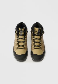 Bottes de randonnée kaki avec une tige en tissu texturé, semelles en caoutchouc noir et lacets noirs, dotées d'un col rembourré et d'un embout renforcé.