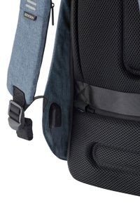 Gray fabric backpack featuring a textured black mesh panel, adjustable strap with buckle, and a zippered pocket on the side.