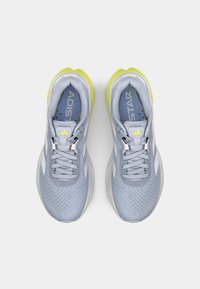 Baskets de sport bleu clair avec une tige en mesh respirant, des accents blancs, une semelle jaune et des lacets fins. Présente un logo bien en vue sur la languette.
