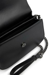 Czarna skórzana torebka o gładkiej fakturze, z zapięciem na zatrzask, dwiema wewnętrznymi komorami oraz odczepianym łańcuszkiem.