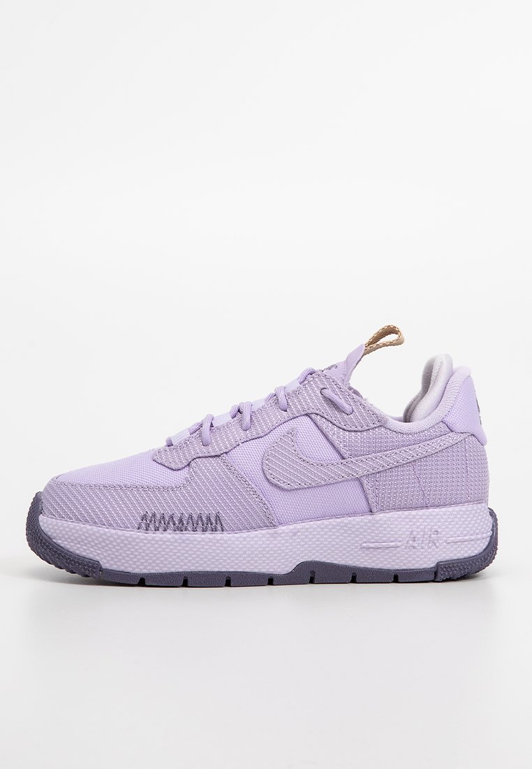 Zapatilla baja de Nike en color púrpura con parte superior de tela texturizada, cierre con cordones y suela blanca gruesa con banda de rodadura oscura.