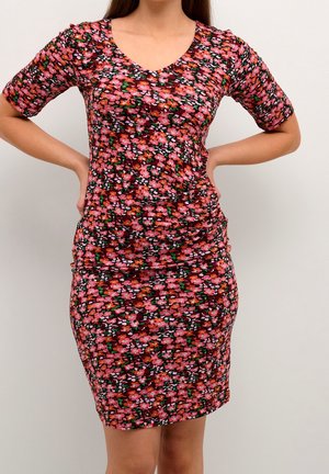 Robe bodycon florale avec un décolleté en V ; dispose de manches courtes et d'une silhouette ajustée. Le matériau présente un mélange de motifs roses, rouges et verts.