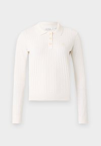 Polo de manga larga de canalé en color crema con un collar clásico, tres botones y un pequeño logo bordado en el pecho. Tejido de punto suave.