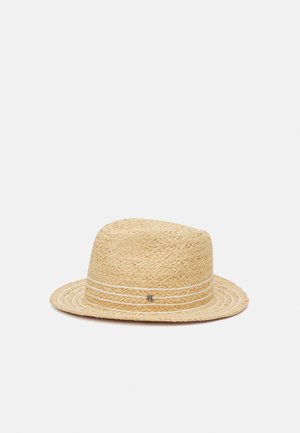 Chapeau fedora en paille tissée beige avec un petit détail de logo en métal sur le ruban, présenté sur un fond clair uni.