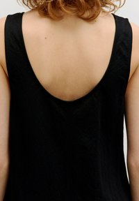 Schwarzes ärmelloses Kleid mit tiefem, rundem Rückenausschnitt, strukturiertem Stoff und einfachem Design. Vielseitig für lässige oder formelle Anlässe.