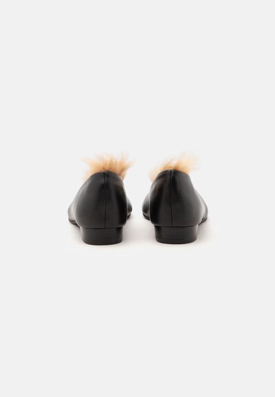 Paire de chaussures plates en cuir noir avec garniture en fourrure beige au talon, vues de dos sur fond blanc.