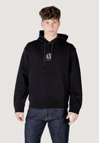 Felpa nera con cappuccio realizzata in misto cotone. Presenta una tasca frontale, cappuccio con cordino e logo bianco al centro del petto. Vestibilità regolare con polsini a coste.