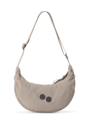 Beige, mondförmige Schultertasche mit verstellbarem Riemen und zwei schwarzen runden Akzenten auf der Vorderseite, freigestellt vor weißem Hintergrund.