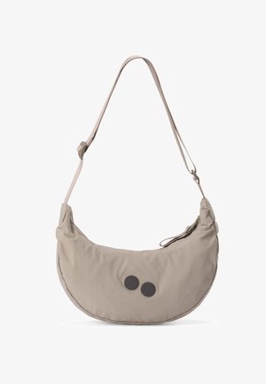 Beige, mondförmige Schultertasche mit verstellbarem Riemen und zwei schwarzen runden Akzenten auf der Vorderseite, freigestellt vor weißem Hintergrund.