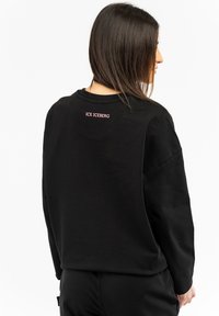 Schwarzes Sweatshirt mit rundem Ausschnitt und langen Ärmeln. Auf der Rückseite steht "ICE ICEBERG" in pinken Buchstaben in der oberen Mitte. Weicher Stoff.