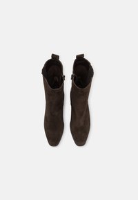 Pair of dark brown suede ankle boots with pointed toes and side zippers, viewed from above on a white background.