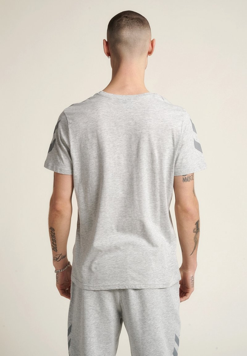 Szara koszulka z krótkim rękawem o okrągłym dekolcie. Miękka tkanina, gładka faktura, z ciemnoszarymi paskami akcentującymi na ramionach. Casualowy fason.