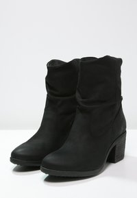 Botas negras hasta el tobillo, hechas de cuero suave, con un diseño arrugado, punta redondeada y tacón apilado. Suela con textura para mayor agarre.