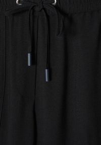 Schwarze Stoffshorts mit strukturierten Oberflächen, ausgestattet mit einer silbernen Öse und einem schwarzen Kordelzug mit blauen Enden sowie seitlichen Taschen.