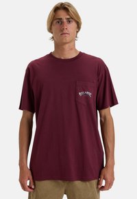 Marlot kortærmet t-shirt lavet af bomuld, med en brystlomme og hvid "Billabong" logo. Løst fit, glat tekstur.