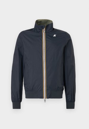 Chaqueta bomber de color marino en material ligero con cuello alto, cierre frontal de dos tonos, puños elásticos y cintura de canalé. Cuenta con un logo en el pecho.