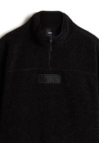 Sudadera de polar negra con cierre de media cremallera, tejido texturizado, parche de logo negro en contraste en la parte delantera y un cuello alto.