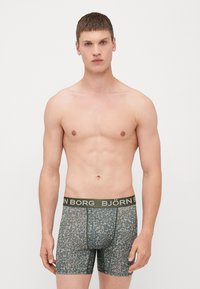 Bokserice v cvetličnem vzorcu, ki vsebuje odtenke zelene in modre, z širokim temnozelenim pasom, na katerem je napis "BJÖRN BORG" v beli barvi.