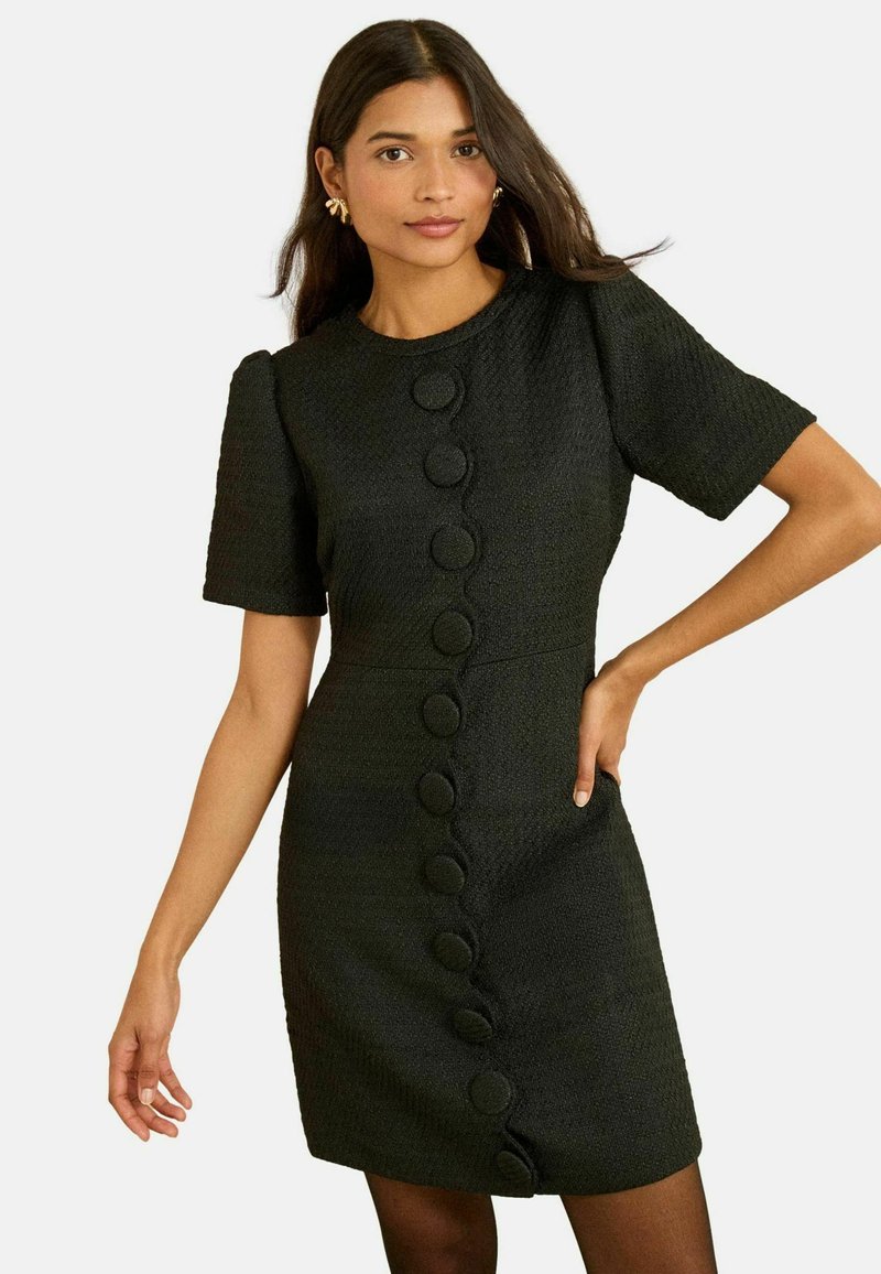 Čierne krátke šaty s krátkym rukávom z textúrovaného materiálu, s priliehavým strihom a veľkými okrúhlymi gombíkmi po celej prednej strane.