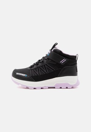 Baskets mid-top noires imperméables avec semelle blanche et lilas, fermeture lacets et velcro, et col rembourré pour le maintien de la cheville.
