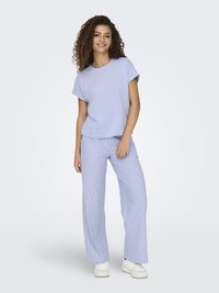 Top a righe blu chiaro a maniche corte abbinato a pantaloni larghi coordinati. Tessuto in misto cotone con una texture morbida. Sneakers bianche.