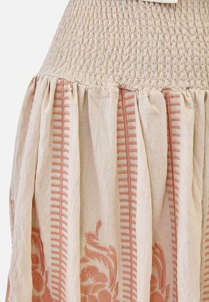 Tela beige con textura fruncida en la parte superior, que pasa a una falda plisada con rayas verticales rosas y un patrón bordado floral.