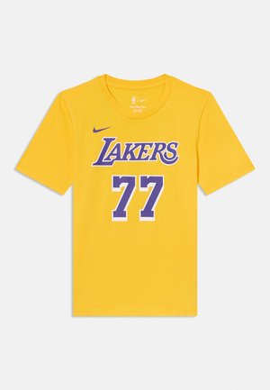 Žluté basketbalové tričko Los Angeles Lakers s krátkými rukávy, fialovým nápisem "LAKERS" a číslem 77 na přední straně, logo Nike nad nápisem.