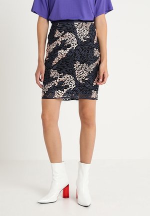 Jupe crayon noire avec un motif de feuilles dans des tons beiges et bleus, assortie à des bottines blanches brillantes avec des talons blocs rouges.