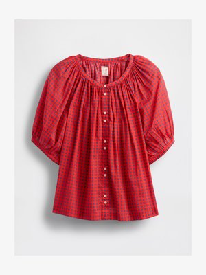 Červená blůza s nabíranými rukávy, s nařaseným výstřihem, zapínáním na knoflíky a kostkovaným vzorem v modré a tmavě modré.
