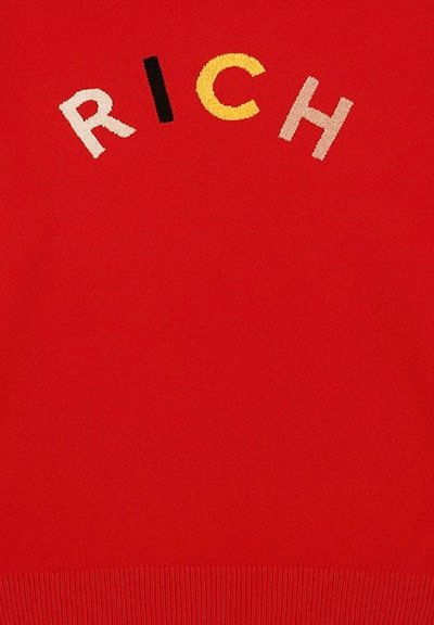 Maglione rosso lavorato a maglia con la parola "RICH" ricamata in multicolori con filato testurizzato. L'orlo a coste aggiunge dettaglio al design.