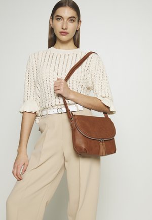 Borsa a tracolla in pelle marrone con pattina arrotondata, chiusura con zip e dettaglio a frange. Texture liscia, cuciture sottili e tracolla regolabile.