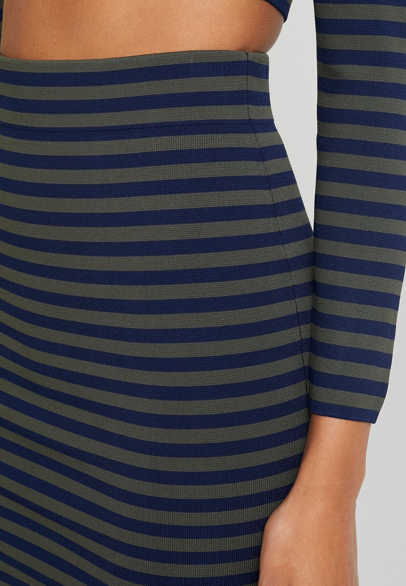 Pruhované pletené šaty s střídajícími se tmavě modrými a olivově zelenými horizontálními pruhy, s přiléhavým střihem a texturovanou žebrovanou látkou.