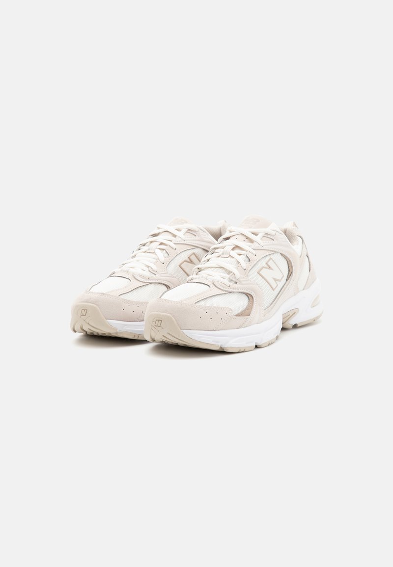 Scarpe sportive bianche caratterizzate da un mix di materiali in rete e suede, con colletto imbottito, allaccio con lacci e dettaglio del logo sul lato.