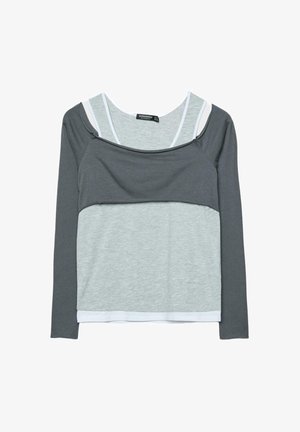 Top a maniche lunghe stile stratificato con strato superiore grigio scuro e strato inferiore grigio chiaro, con rifiniture bianche e scollo rotondo.
