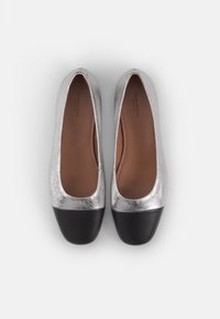 Zilveren platte schoenen met een glanzende bovenkant en een zwarte neus. Gladde textuur met een gevoerd binnenzool. Rond ontwerp, minimale details.