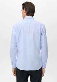 Lichtblauw overhemd met lange mouwen en een button-down kraag, gemaakt van een soepele stof. Het heeft knopenmanchetten en een ronde zoom.