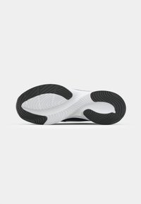 Sola de sapato com um design em preto e branco, apresentando padrões de borracha texturizada para melhor aderência, formas curvas e sulcos acentuados.