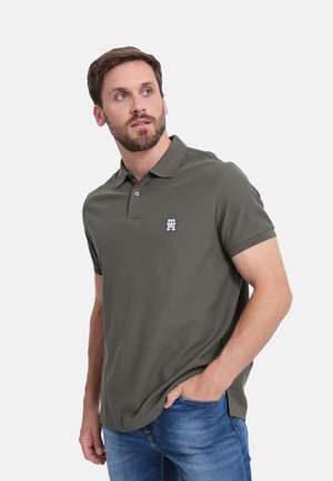 Polo de color verde oliva con un collar de canalé, mangas cortas y un logo blanco en el lado izquierdo del pecho. Tejido suave con un corte clásico.