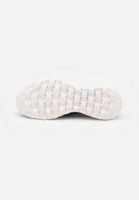 Die Schuhsohle besteht aus einem strukturierten weißen Gummi mit erhabenen Mustern und Rillen für besseren Halt. Abgerundete Zehenpartie und gepolsterter Fersenbereich.
