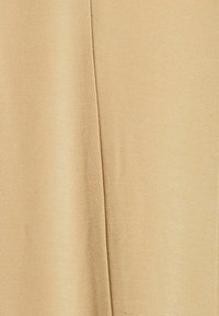 Beige kangas, jossa on hieno, teksturoitu kudonta ja pystysuora sauma keskellä.