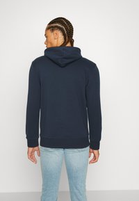 Sudadera azul marino con capucha, hecha de una mezcla de algodón, cuenta con puños y dobladillo acanalados, y una textura suave.