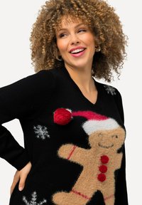 Zwarte trui met een fluffy gemberkoekman ontwerp, voorzien van een rode pompon, witte hoed en sneeuwvlokaccenten. V-hals en lange mouwen.