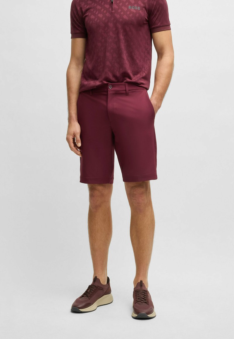 Burgundyröda shorts med skräddarsydd passform, tillverkade av lättviktsmaterial. Matchas med en polo med en subtilt mönster och logotyp.
