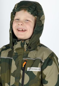 Camo-jack met groene en beige kleuren, een rits aan de voorkant met een oranje trekband en een gevoerde capuchon. Het logo "SWEDEMOUNT" is zichtbaar.