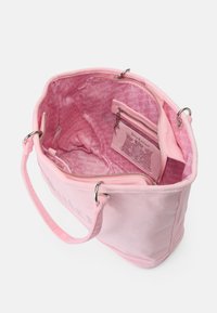 Saco tote de tecido rosa com uma textura suave, hardware prateado e um interior com um padrão de logotipo rosa repetido e um bolso com fecho.